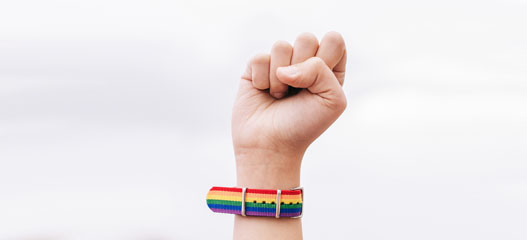 una mano con la correa del reloj con los colores LGTBIQ+