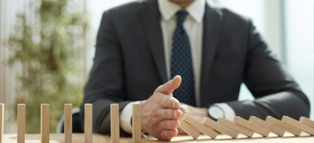 Empresario frenando un dominó en una oficina