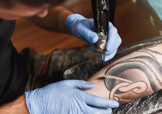 Tatuador mientras tatúa un brazo